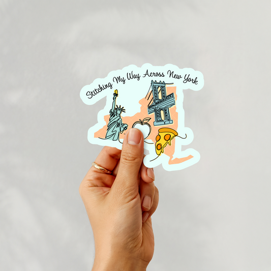 Sticker featuring New York icons and stitching motifs held in hand.