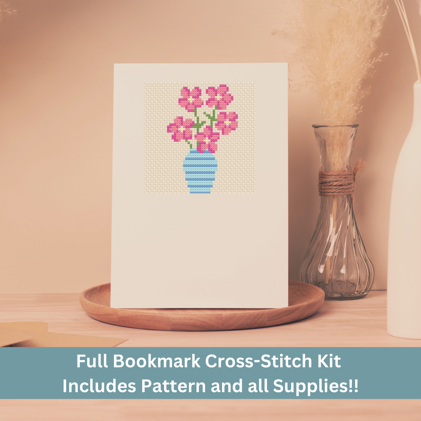 Cross-stitch greeting card featuring a pink bouquet in a blue vase, stitched on Aida cloth.