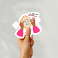 A hand holding a playful embroidery sticker with diverse hands and the quote “I Like Big Hoops & I Cannot Lie”