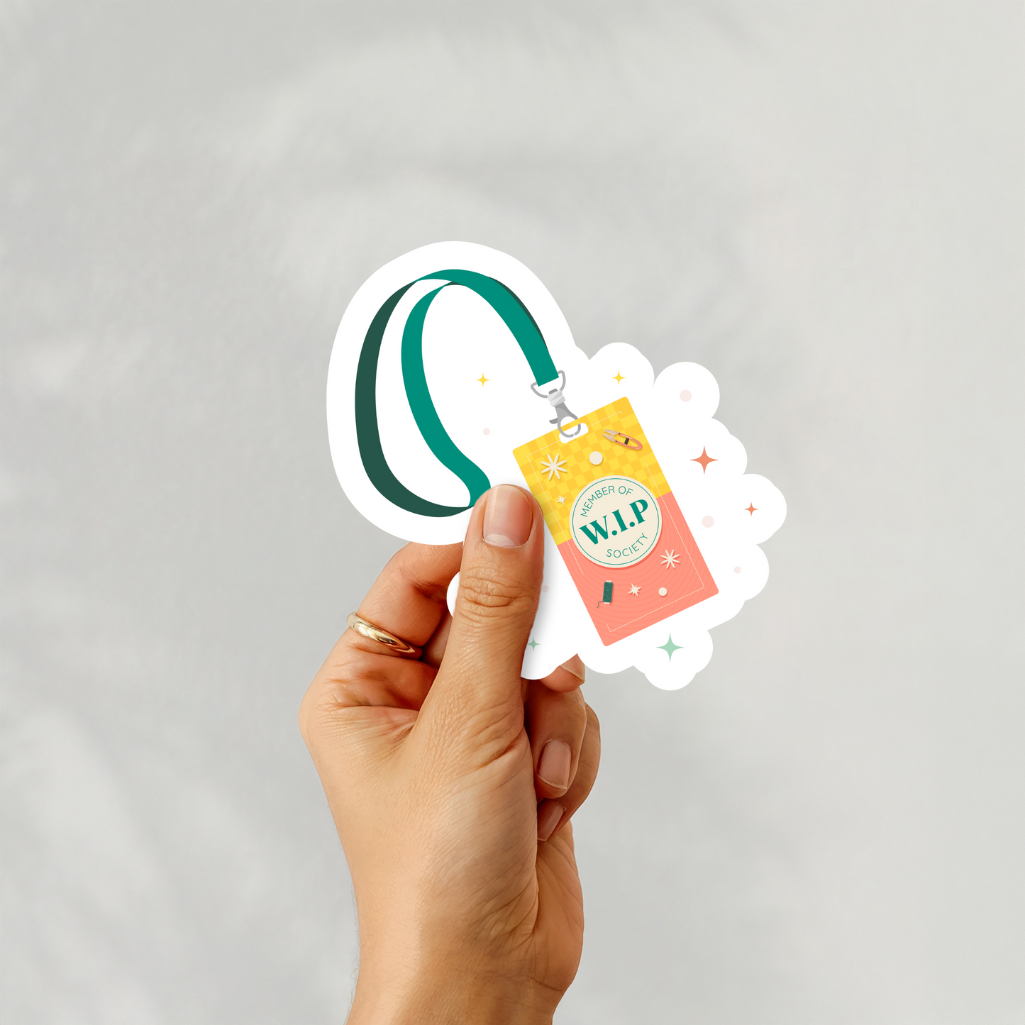 Hand holding ‘Member of W.I.P. Society’ badge sticker with lanyard design in cross stitch theme