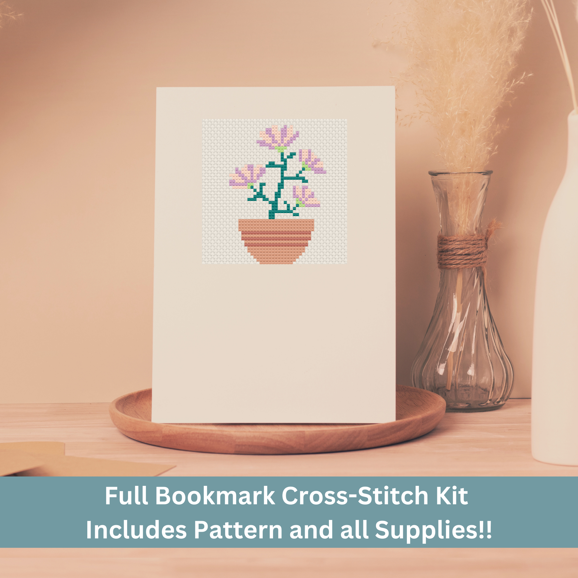 Cross-stitch greeting card featuring a potted plant with blooming pink flowers, stitched on Aida cloth.