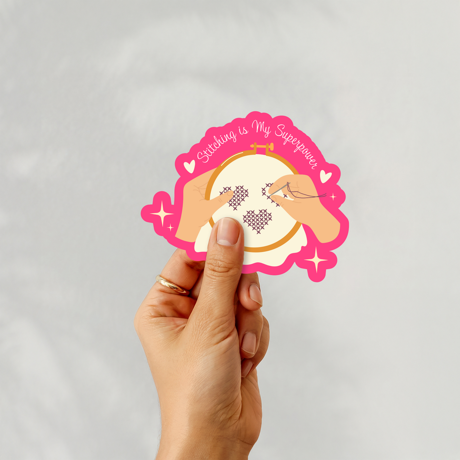 Sticker showing hands stitching hearts in a hoop, reading “Stitching is My Superpower.”